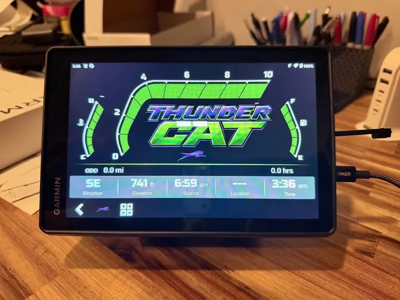 G8 cluster showing a custom green theme, sitting on a workbench connected by USB, with green gauges either side of a large centre graphic.